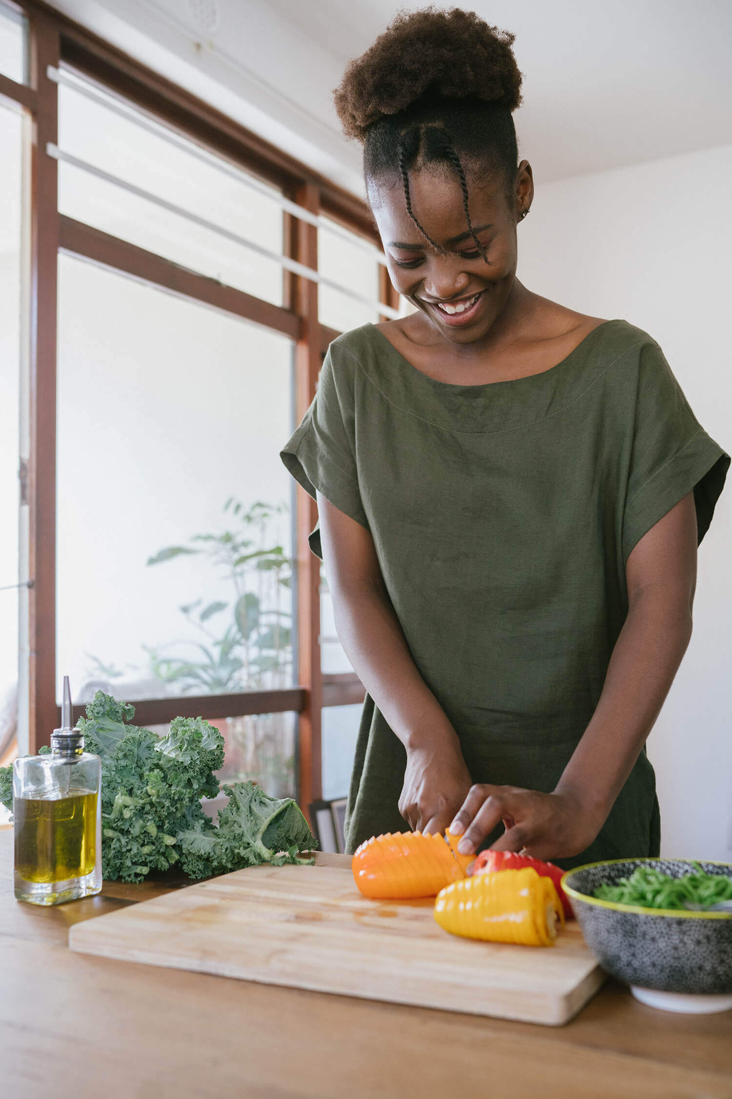 woman in-green tank top cutting orange bell pepper