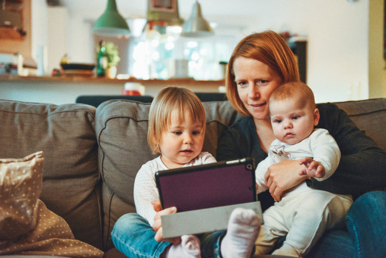 Mom on the couch with daughters showing them things on an iPad