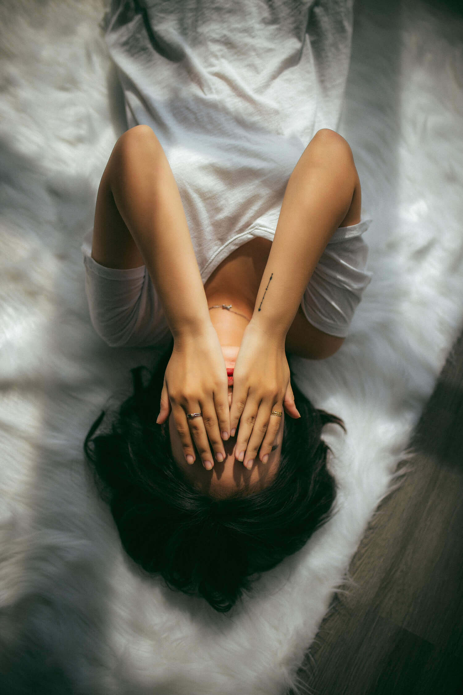 Woman laying in bed with her hands over her face.