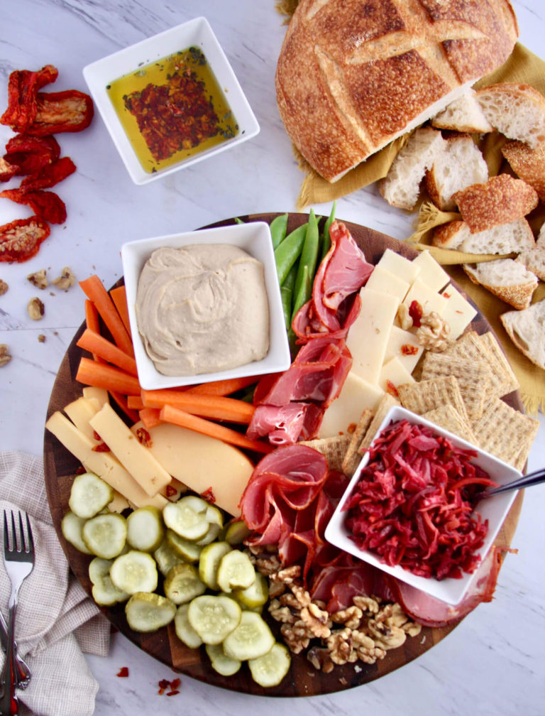 Overhead of a charcuterie board filled with probiotic foods next to a sliced loaf of bread